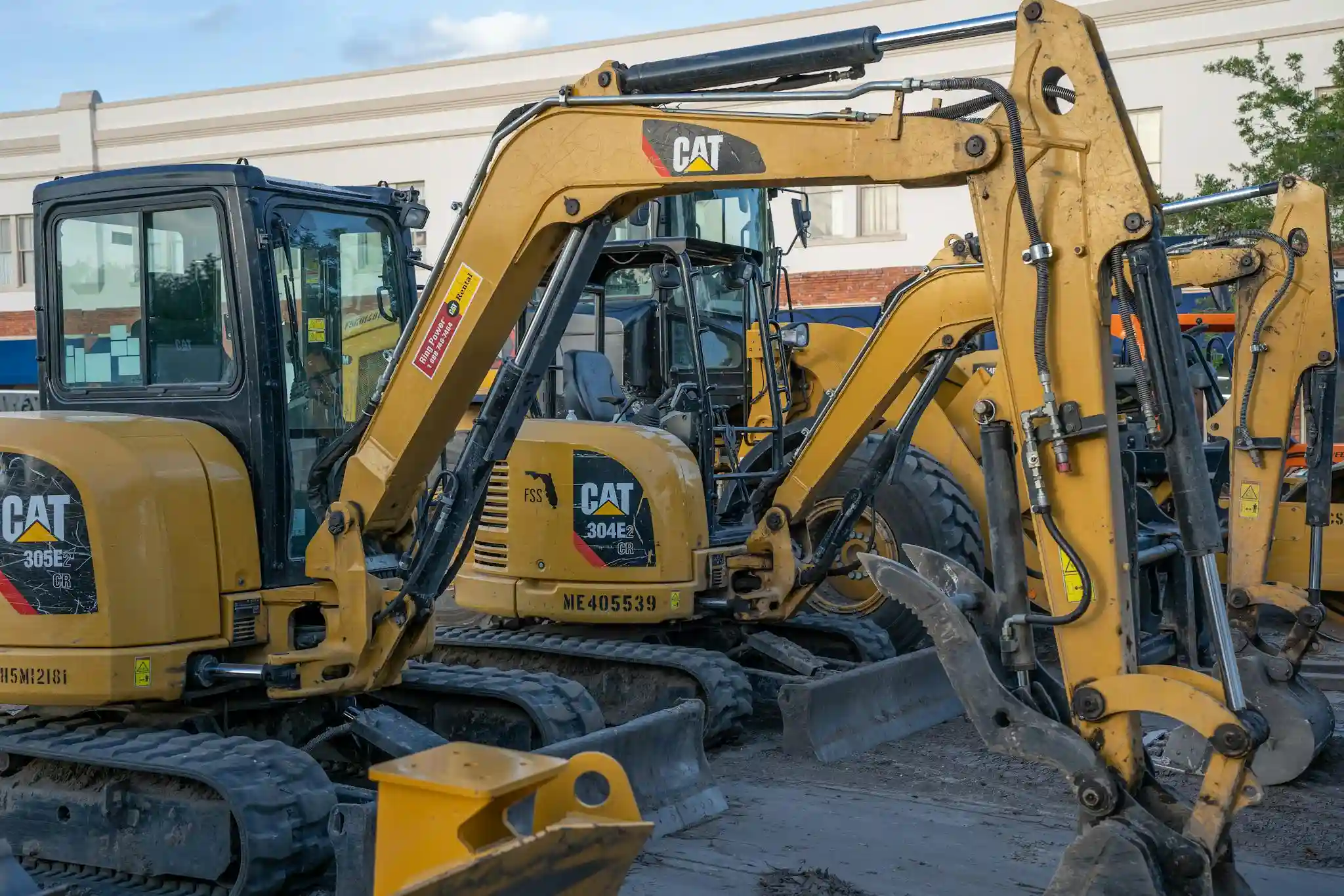 A row of parked CAT excavators at a construction site, ready for heavy duty work With Adblue / DEF Delete Emulator Fitted