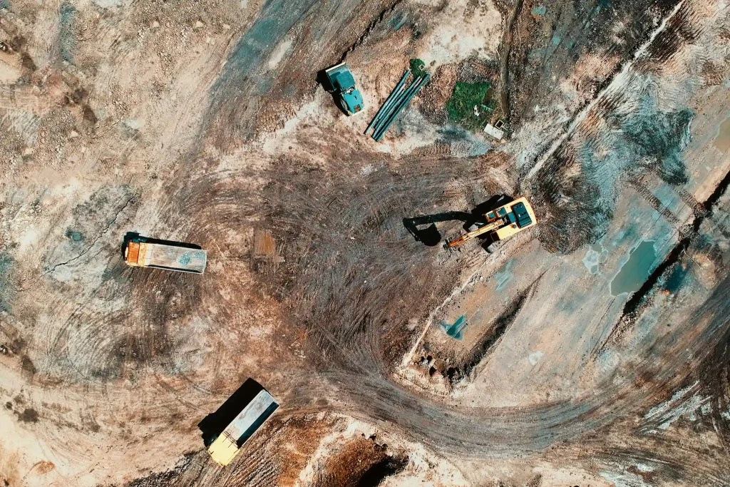 High-angle aerial view of construction site with earthmoving equipment and trucks. The machines must have the DEF Delete emulators fitted as no body is standing around smoking away killing time waiting for machines to be fixed.