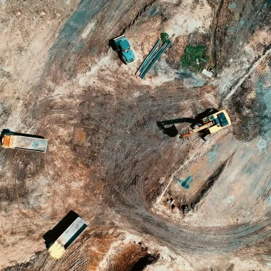 High-angle aerial view of construction site with earthmoving equipment and trucks. The machines must have the DEF Delete emulators fitted as no body is standing around smoking away killing time waiting for machines to be fixed.