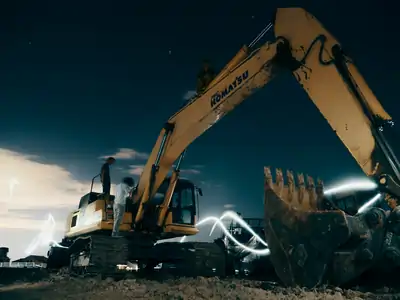 A powerful excavator at a construction site under the night sky, with workers around trying to get it working again, it has got DEF Faults and they might just need to set fire to the machine